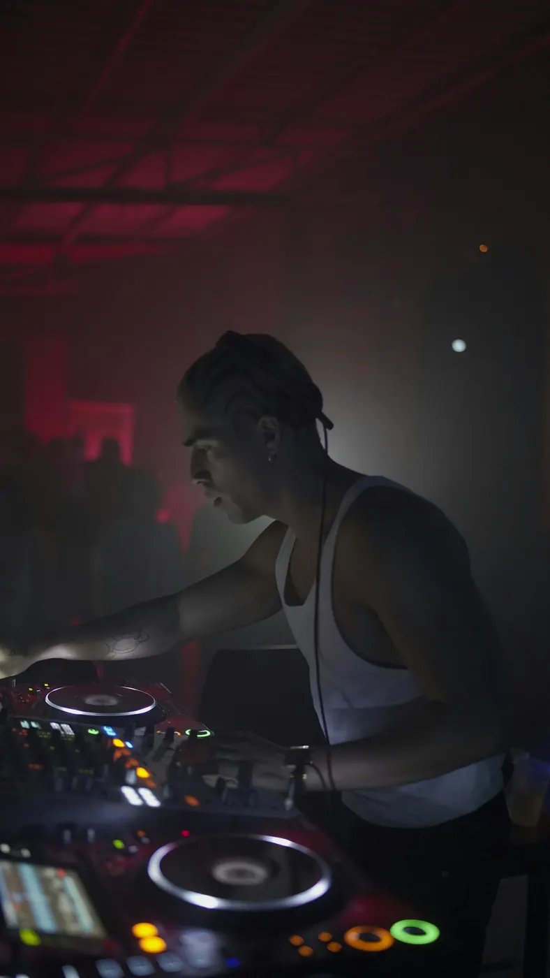 DJ mezclando en tornamesas entre luces y humo