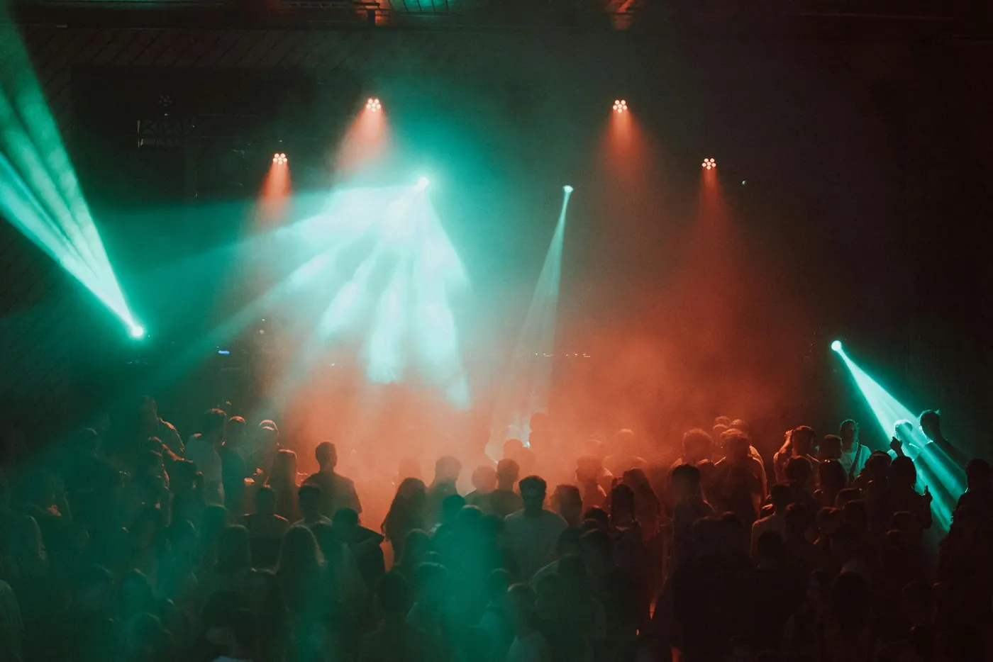 Público bailando bajo luces verdes y rosas del escenario